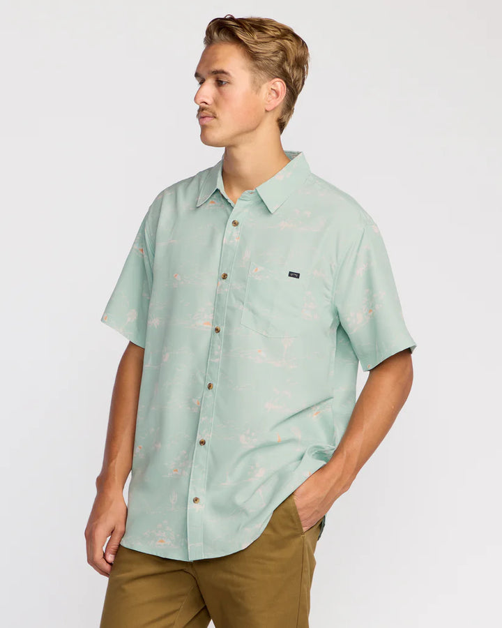 Man wearing a light green short-sleeve shirt with a subtle pattern on a plain background