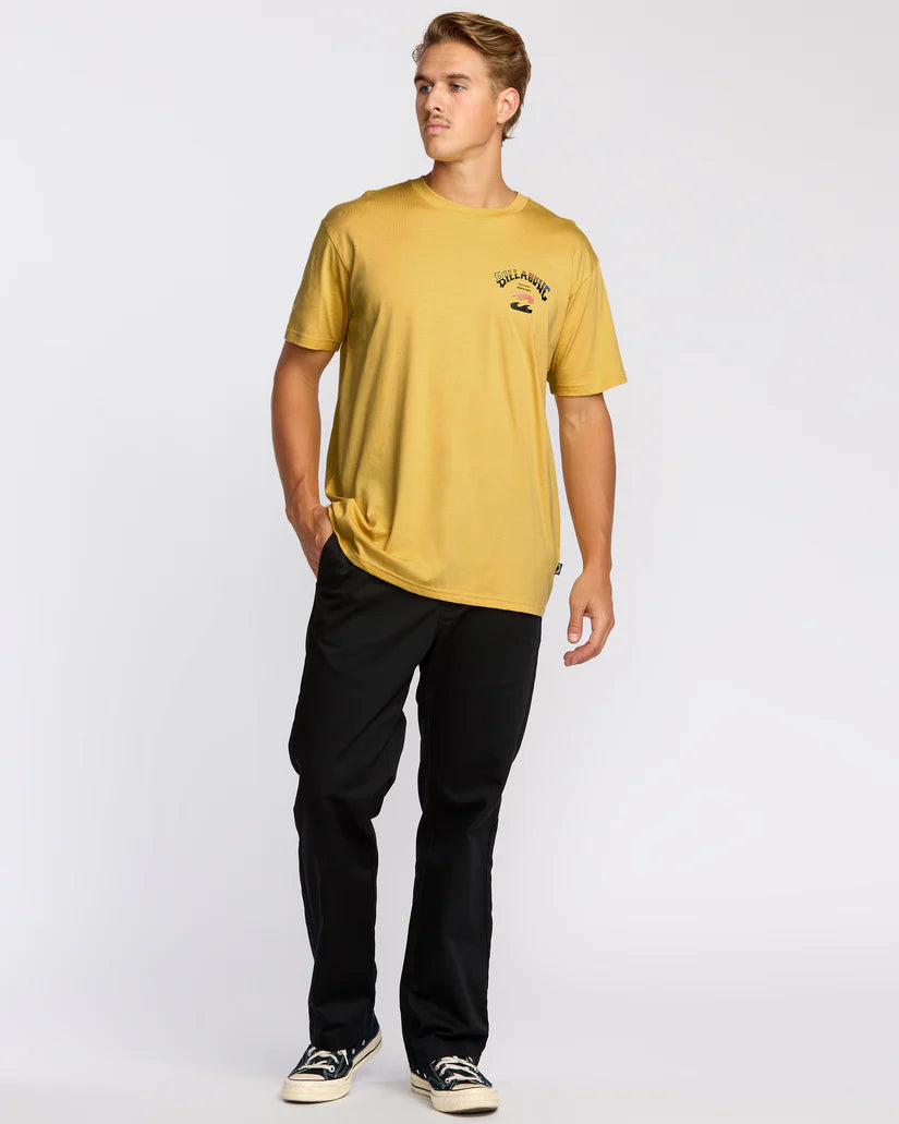 Man wearing a mustard yellow t-shirt with a logo and black pants on a white background